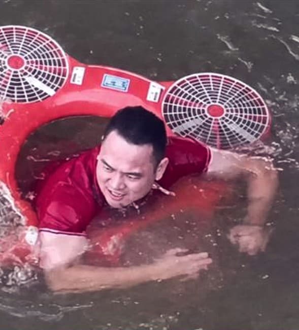 A person in the water holding onto the AquaBot Flying Lifeboat